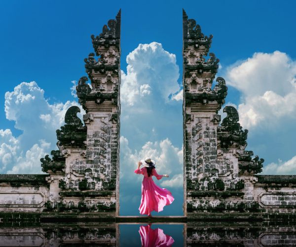 Young woman standing in temple gates at Lempuyang Luhur temple in Bali, Indonesia. Vintage tone.